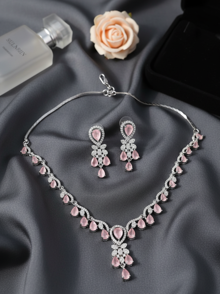 Pink jewelry set with necklace and earrings on a gray fabric background